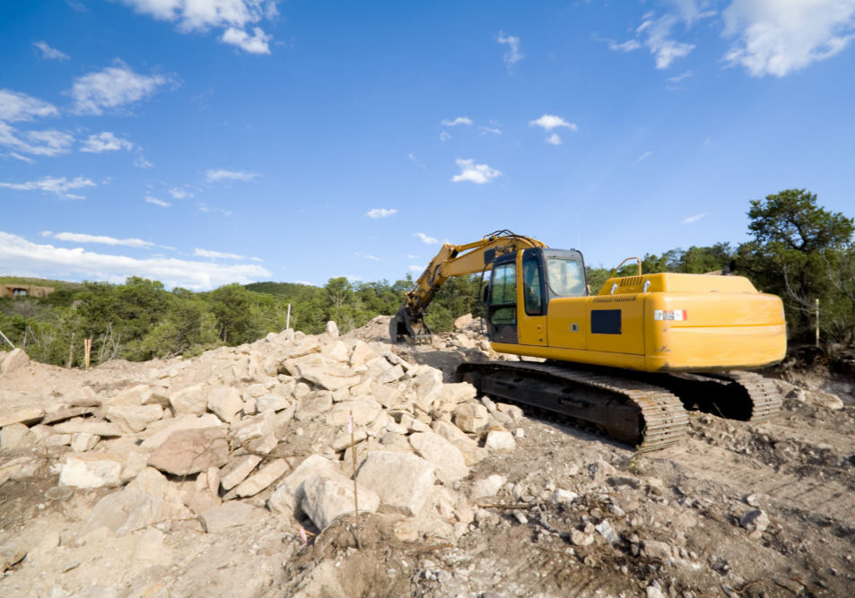 A crane tractor digging through the rocks